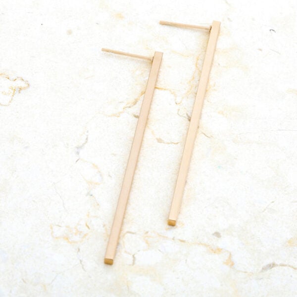 Angled view of the goldtone earrings showing the metal's plated surface sheen