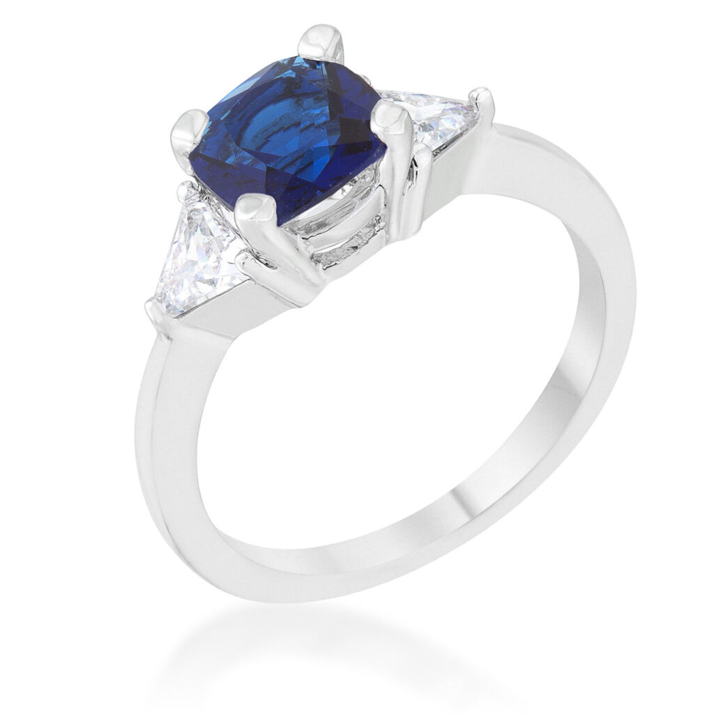 Sapphire-colored cubic zirconia ring with cushion and trillion cuts in a prong setting, rhodium plated over lead free alloy (brass).