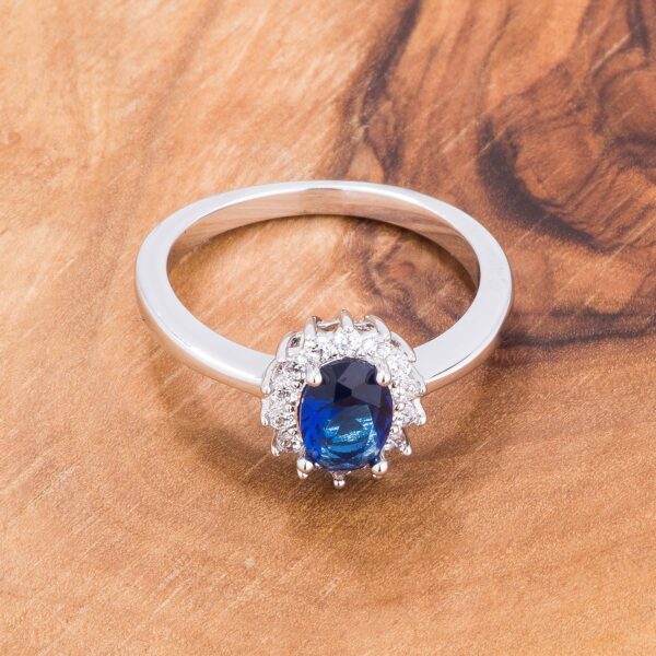 Silvertone oval ring with blue cubic zirconia shown at an angle to display the setting