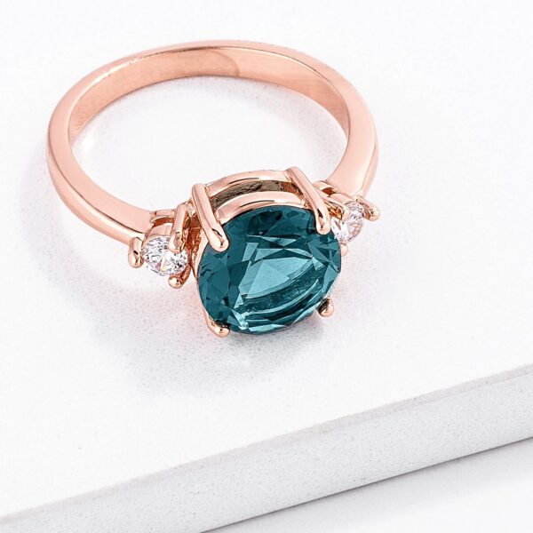 Three-stone engagement ring in rose gold tone over lead free alloy (brass), with round blue green cubic zirconia