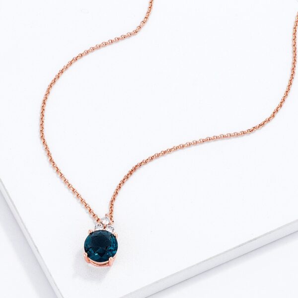 Close-up angle of the rose goldtone plated pendant showing the round blue green cubic zirconia stones