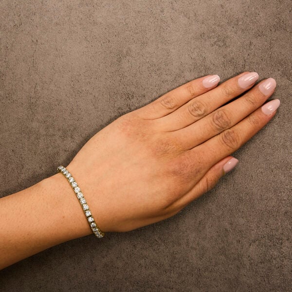Yellow gold diamond tennis bracelet worn on a wrist