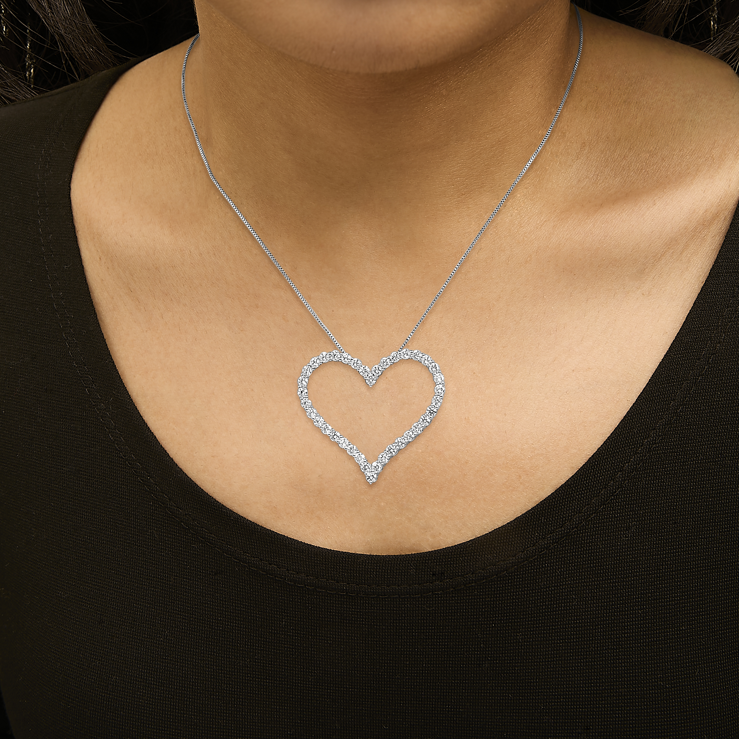 Open heart diamond pendant necklace worn at the collarbone by a model