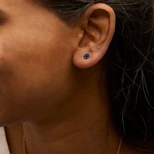 Sapphire stud earrings worn on a model's ear
