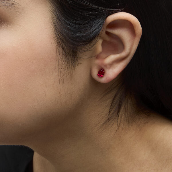 Pear ruby stud earrings shown worn on an ear
