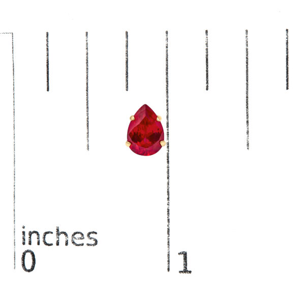 Pear ruby stud earrings shown next to a scale reference to indicate size
