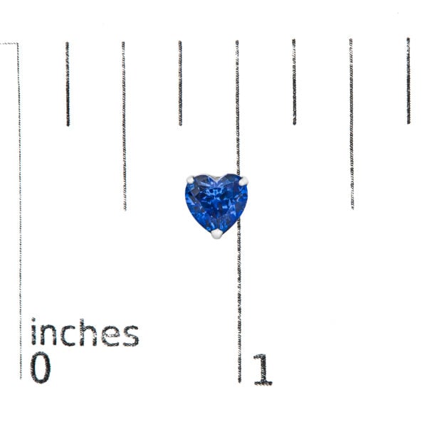Platinum heart sapphire stud earrings next to a scale reference showing their small size
