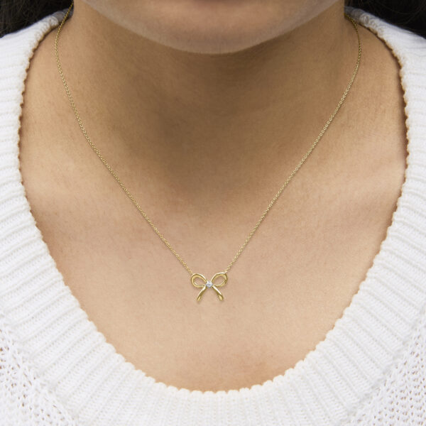 Bow tie pendant necklace shown worn on a model, resting at the neckline