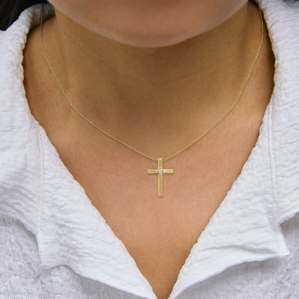 Cross pendant necklace worn on a neck, showing the cable chain and clasp placement