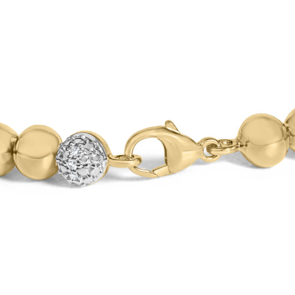 Close-up of dome bead links on the 24K gold plated bracelet showing pave-set round diamonds