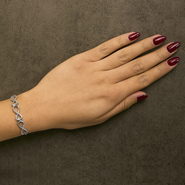 Bolo bracelet worn on a wrist, showing the infinity heart links and diamonds in place